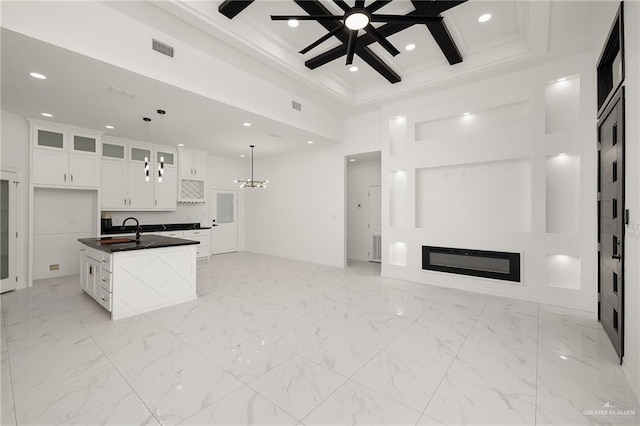 kitchen featuring dark countertops, visible vents, open floor plan, a glass covered fireplace, and a sink