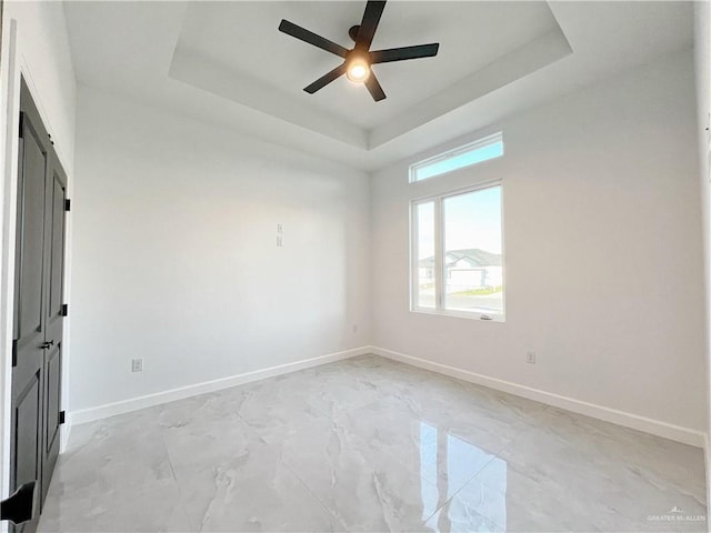 spare room featuring ceiling fan and a tray ceiling