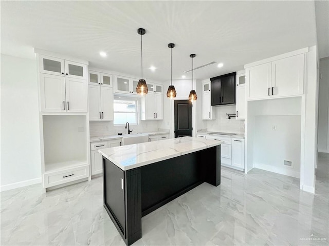 kitchen featuring light stone countertops, a center island, white cabinets, and decorative light fixtures