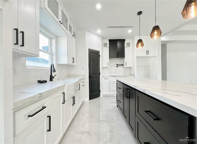 kitchen with white cabinetry, sink, light stone countertops, tasteful backsplash, and decorative light fixtures