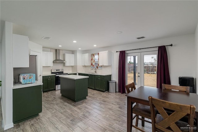 kitchen featuring wall chimney exhaust hood, green cabinetry, a kitchen island, electric stove, and white cabinets