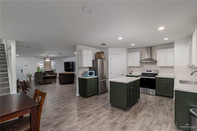 kitchen with appliances with stainless steel finishes, white cabinetry, sink, green cabinets, and wall chimney exhaust hood