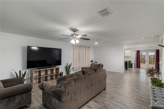 living room featuring french doors, ceiling fan, and light hardwood / wood-style flooring