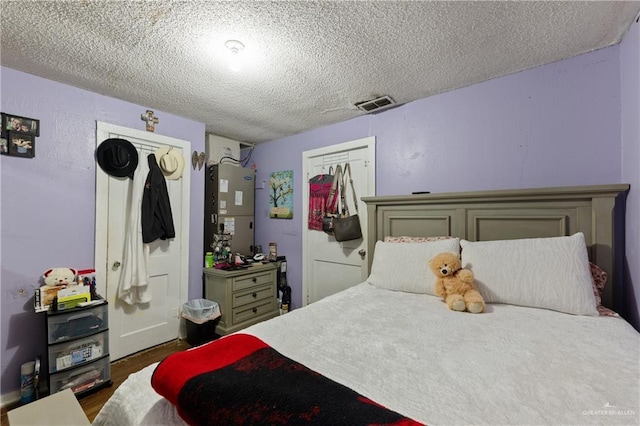 1914 W Barcelona Ave, Harlingen, TX 78550 - bedroom with heating unit, wood finished floors, a textured ceiling, and visible vents