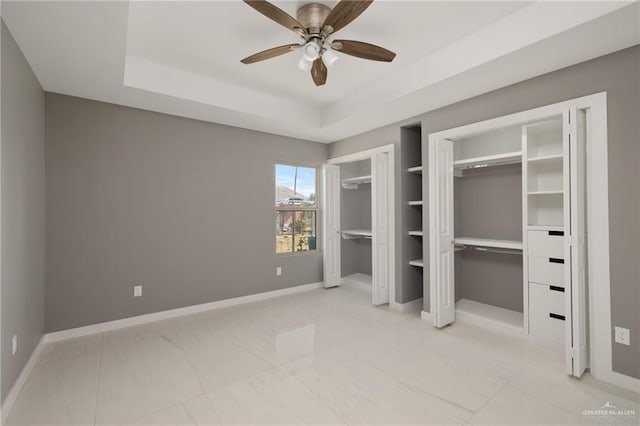 unfurnished bedroom with ceiling fan and a tray ceiling