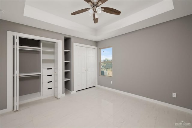 unfurnished bedroom with a raised ceiling and ceiling fan