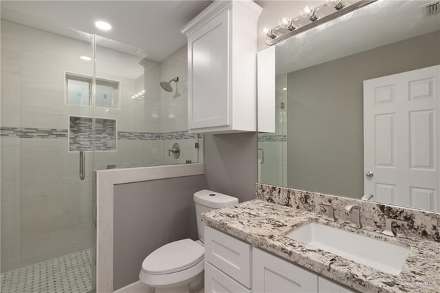 bathroom featuring toilet, a shower with shower door, and vanity