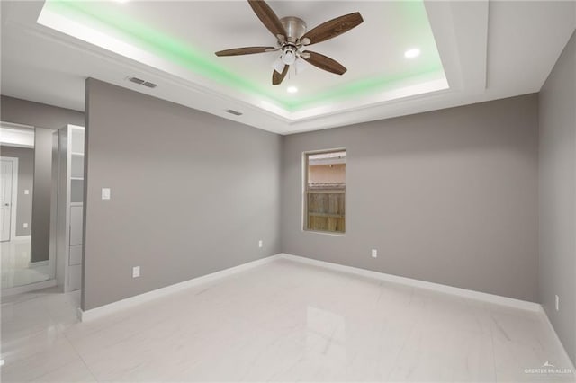 unfurnished room featuring ceiling fan and a tray ceiling