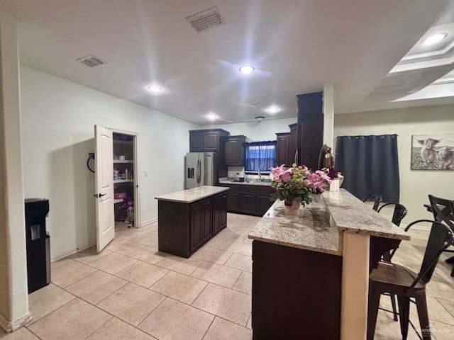 816 Leal St, Mission, TX 78572 - kitchen with visible vents, a peninsula, a kitchen island, a kitchen breakfast bar, and stainless steel fridge