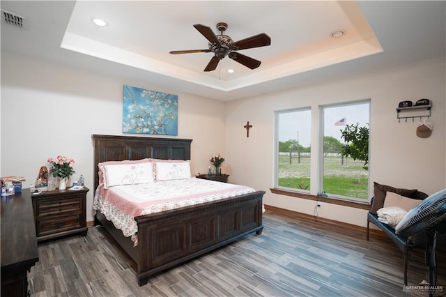 bedroom featuring a tray ceiling, visible vents, recessed lighting, and wood finished floors