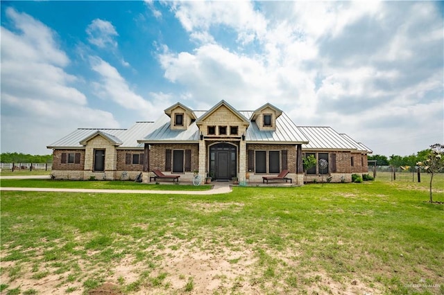 view of front facade with metal roof, a standing seam roof, brick siding, and a front yard