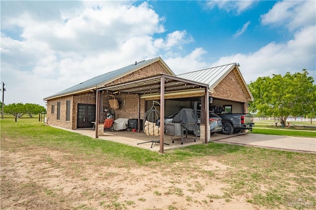 exterior space with driveway, brick siding, metal roof, a garage, and a yard