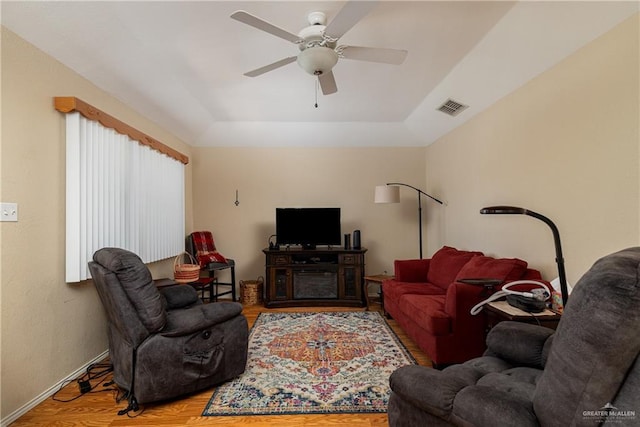 living area featuring ceiling fan, a raised ceiling, wood finished floors, and visible vents