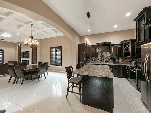 kitchen featuring a breakfast bar, appliances with stainless steel finishes, a kitchen island, pendant lighting, and decorative backsplash