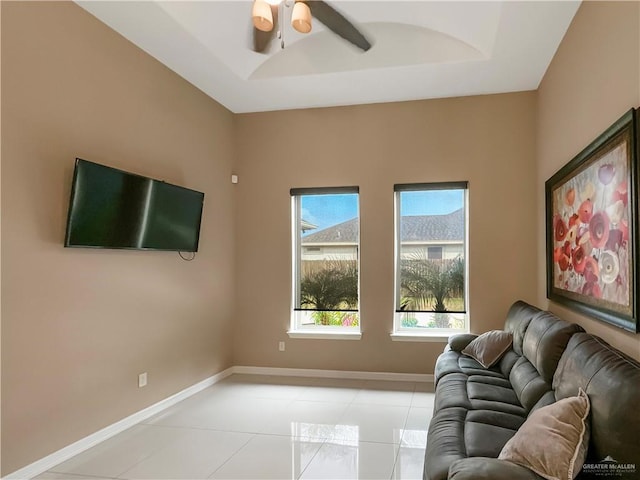 tiled living room featuring ceiling fan and a raised ceiling