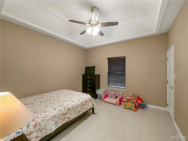 bedroom featuring ceiling fan, a raised ceiling, and tile patterned flooring