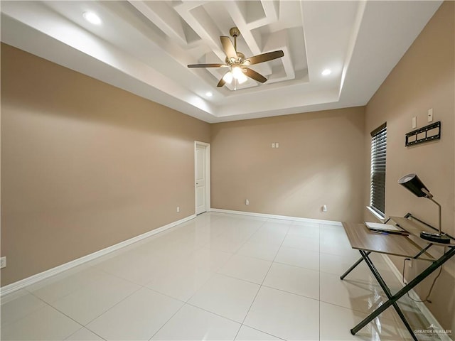 tiled spare room featuring ceiling fan and a tray ceiling