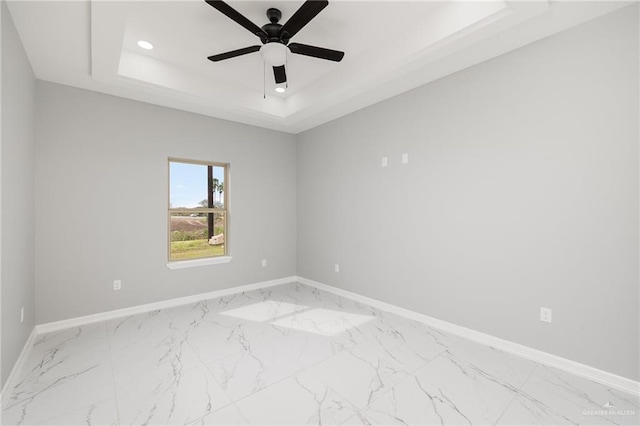 unfurnished room with ceiling fan and a tray ceiling