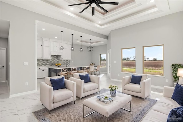 living room featuring a tray ceiling, plenty of natural light, and ceiling fan