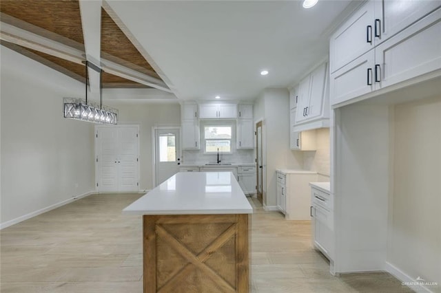 kitchen featuring decorative backsplash, decorative light fixtures, a kitchen island, white cabinets, and sink