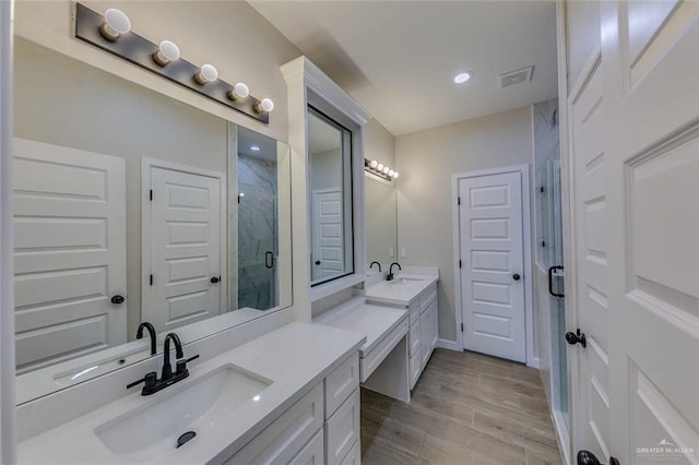 bathroom with a shower with shower door and vanity