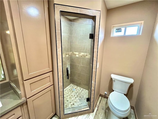 bathroom with wood-type flooring, a shower with shower door, and toilet