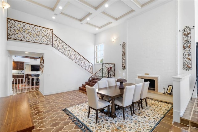 dining room featuring hardwood / wood-style flooring, beam ceiling, a high ceiling, and coffered ceiling