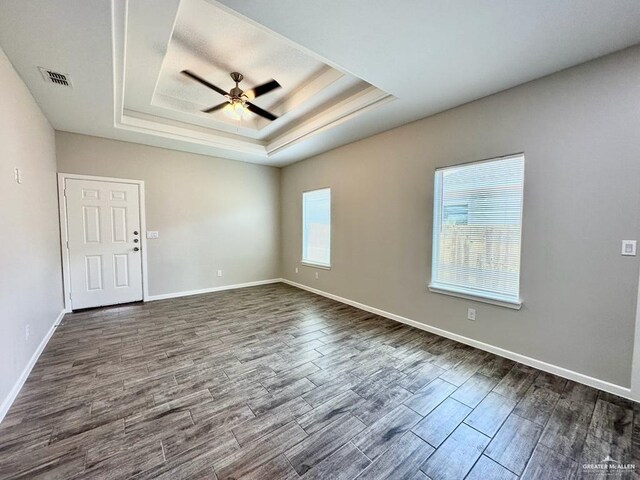 unfurnished room with a raised ceiling, ceiling fan, and hardwood / wood-style flooring