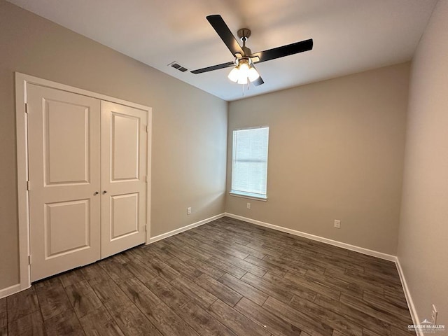 unfurnished bedroom with ceiling fan, dark wood-type flooring, and a closet