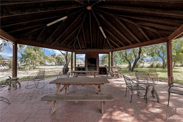 view of patio with a gazebo and an outdoor brick fireplace