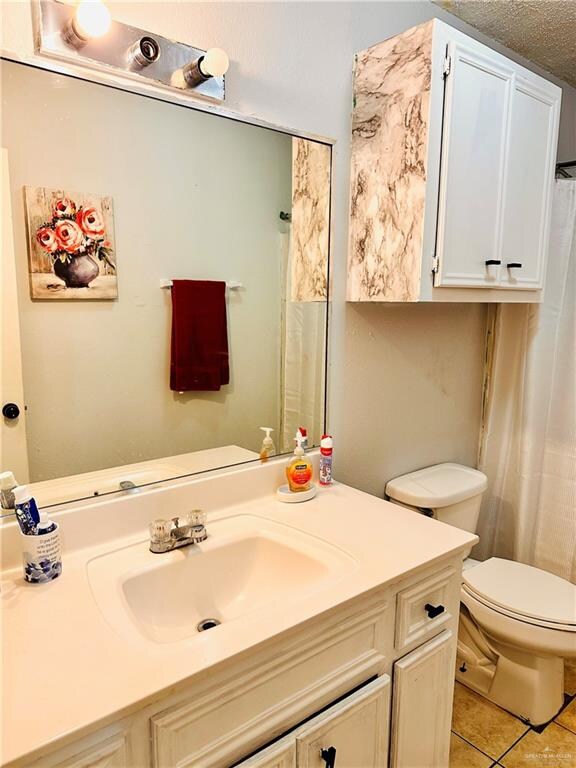 bathroom featuring tile patterned flooring, a textured ceiling, vanity, and toilet