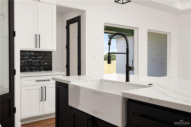 kitchen featuring white cabinets, light stone counters, and a sink