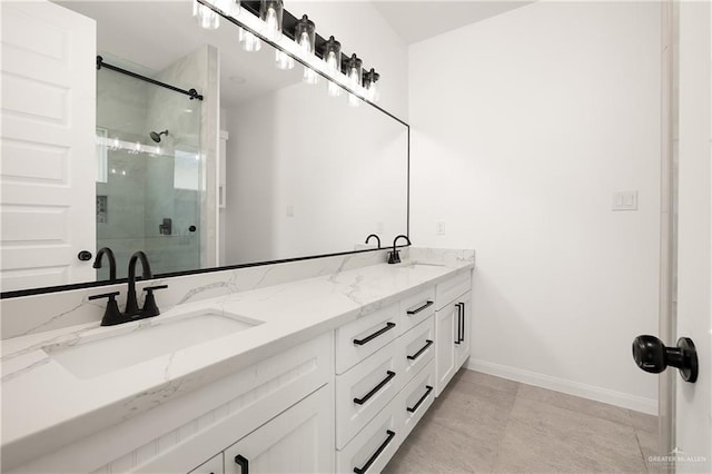 full bathroom featuring double vanity, a shower stall, baseboards, and a sink