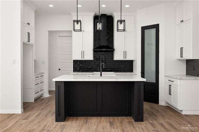 kitchen with light wood finished floors, tasteful backsplash, recessed lighting, wall chimney range hood, and baseboards