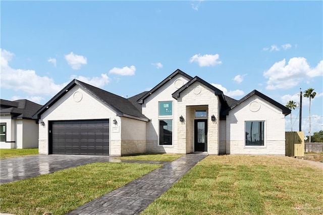 view of front facade with driveway, stone siding, fence, a front yard, and a garage