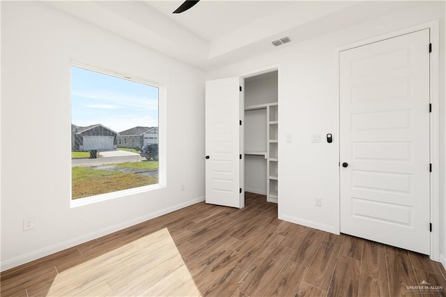 unfurnished bedroom featuring visible vents, baseboards, wood finished floors, and a ceiling fan