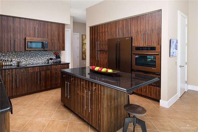 310-A Padre Blvd Unit 3102, South Padre Island, TX 78597 - kitchen with stainless steel appliances, light tile patterned floors, a kitchen bar, a kitchen island, and decorative backsplash