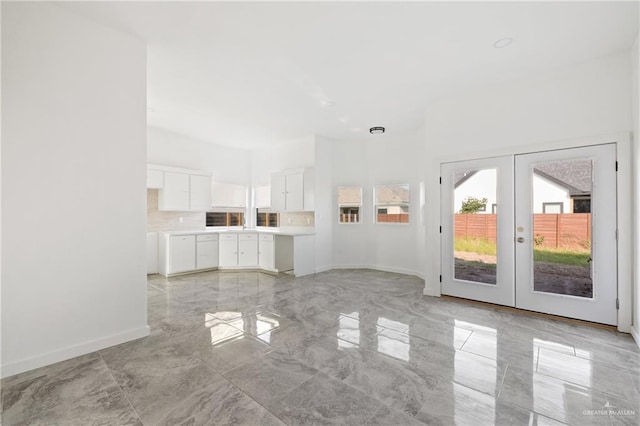 unfurnished living room featuring french doors, marble finish floor, and baseboards