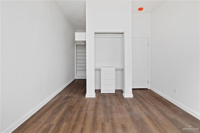 unfurnished bedroom with dark wood-style floors, baseboards, and a closet