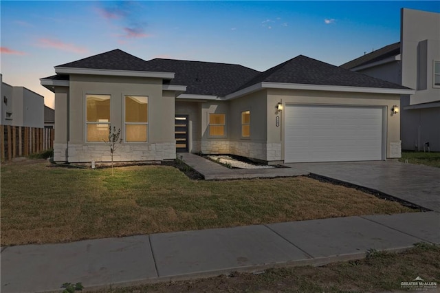 view of front of house featuring driveway, stone siding, an attached garage, fence, and stucco siding