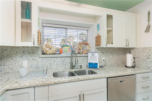 kitchen with tasteful backsplash, white cabinetry, sink, and stainless steel dishwasher