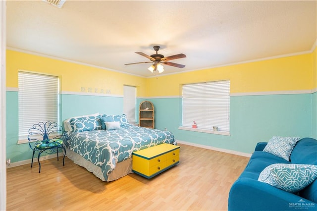 bedroom featuring multiple windows, hardwood / wood-style floors, ceiling fan, and crown molding