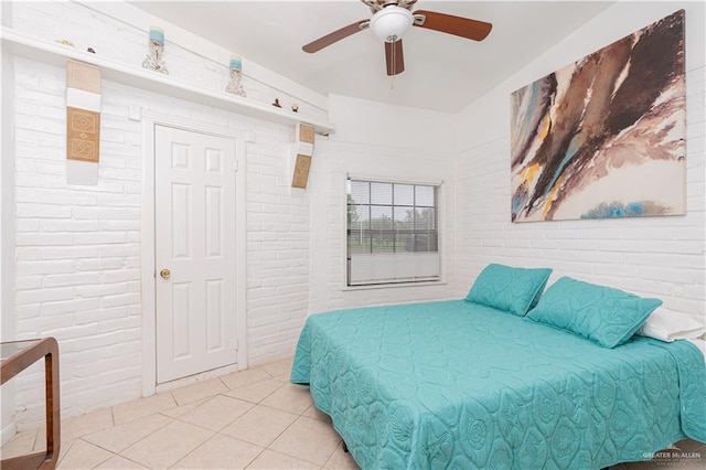 bedroom featuring ceiling fan, light tile patterned flooring, and brick wall