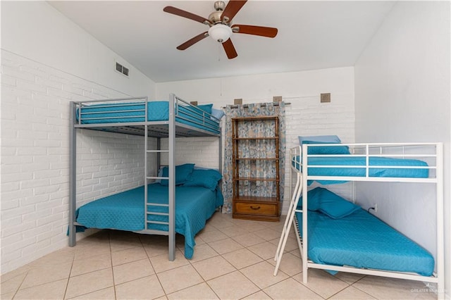 tiled bedroom with ceiling fan and brick wall