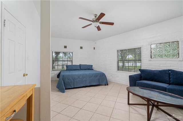 tiled bedroom featuring ceiling fan and brick wall