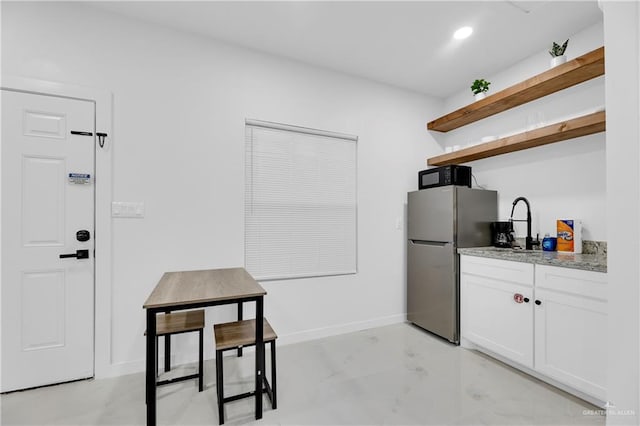 kitchen with white cabinets, stainless steel fridge, and sink