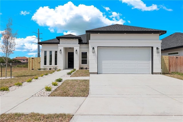 view of front of property with a garage, stucco siding, driveway, and fence