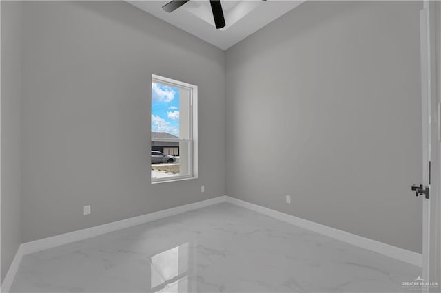 empty room featuring ceiling fan, marble finish floor, and baseboards