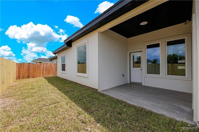 exterior space featuring stucco siding, a yard, a patio, and fence