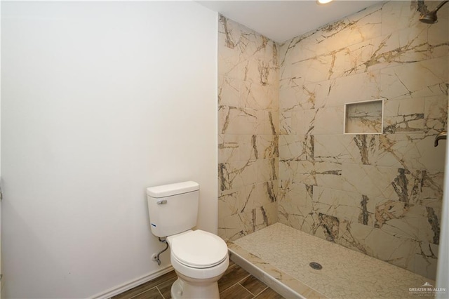 bathroom featuring toilet and a tile shower